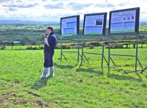 Scientist presenting in front of posters displayed in a field Scientist presenting in front of posters displayed in a field